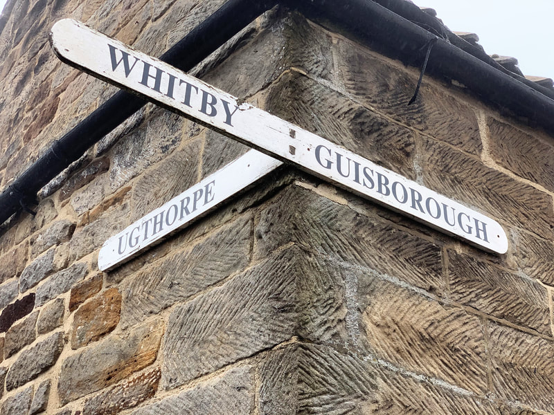 Image of old Whitby Guisborough Ugthorpe road sign attached to corner of property in Lythe